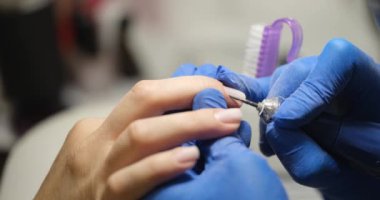 Manikürcüdeki kadın güzellik salonundaki bir kuaförde manikür yaptırıyor. Elektrikli oje makinesi kullanıyor. Teknoloji ve tırnak bakımı kavramı