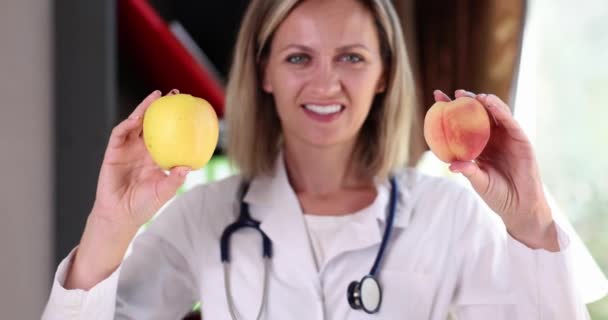 美丽的女医生拿着苹果和桃果实微笑的画像 健康食品 饮食和维生素 — 图库视频影像