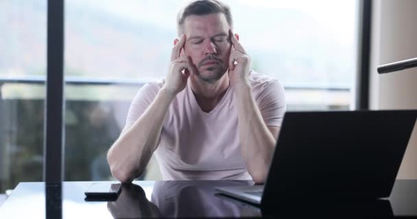 若い男は自宅で働いて片頭痛に苦しんでいます 病気の再管理や屋外作業を頭 — ストック動画
