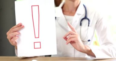 Doktor baş parmak ve kırmızı ünlem işareti tutuyor. Dikkat ve sağlık önleme