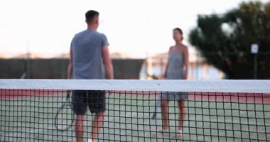 Çift tenis oynadıktan sonra oyun alanını terk ediyor. Güzel bir kadın ve yakışıklı bir erkek tenis kortundan sonra sarılıp ayrılırlar.