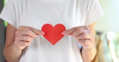 Kadın eli kağıt kırmızı bir kalp tutar. Aşk kavramı aşık olur ve sevgililer gününe