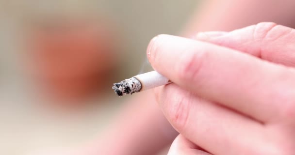 若い男の手がタバコを燃やしている 喫煙や腫瘍の害 — ストック動画