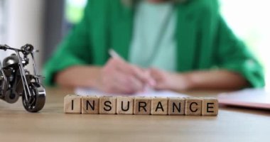 Ajan, oyuncak motosikletin yanında oturuyor ve tahta küpün kelime sigortası, yakın çekim 4K film yavaş çekim. Araba sigortası kavramı