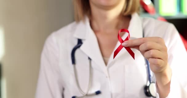 エイズとHivとの闘いの赤いリボンのシンボルを示す女性医師と人差し指を閉じる4K映画スローモーション 免疫不全の概念を持つ患者のためのボランティアの助け — ストック動画