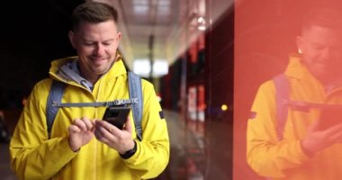 Erkek turist gülümseyip mesaj atıyor ya da telefondaki konuma bakıyor. Adam akıllı telefonuyla caddede duran yolu seçiyor.