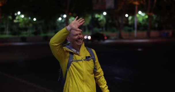 游客看到他的熟人 高兴地举起手在晚上的街上打招呼 出租车的呼叫和喜悦与快乐的情绪 — 图库视频影像