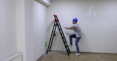 Mutlu erkek tamirci merdivene tırmanıyor ve ellerini kaldırıyor. Profesyonel kalite iş bitirme konsepti