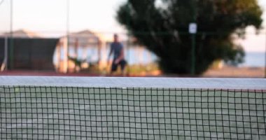 Profesyonel olarak donanımlı tenis oyuncusu ve arka plandaki tenis oyuncusu tenis topuna raketle vuruyor. Tenis oyunu
