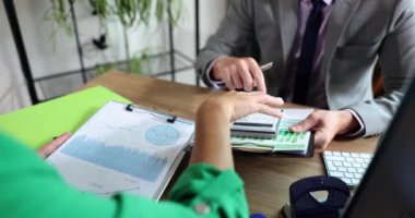 İş kadını ve ortağı, pazarlama ve vergi planlama için mali tabloya işaret ediyor. Muhasebe istatistikleri ve analitik araştırmaların takım çalışması