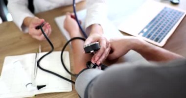 Doktor hastanedeki kan basıncını ölçmek için stetoskopla sfinometre kullanıyor. Atardamar hipertansiyonunun kontrolü