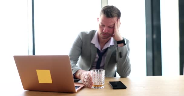 一位悲伤的商人在工作场所的笔记本电脑前喝威士忌的肖像 酗酒会导致工作中的抑郁症 — 图库视频影像