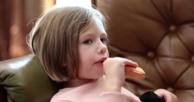 Çocuk portresi peynirli sosisli sandviç yiyor. Çocuklar için atıştırmalıklar