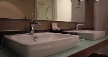 Otel odasında musluklu iki lavabo var. Banyoda şık hijyenik malzeme seçimi.