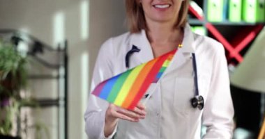 Doktor klinikte LGBT gökkuşağı bayrağı tutuyor. Ulusal sağlık sistemi konsepti LGBT gay, biseksüel ve transseksüel lezbiyenler
