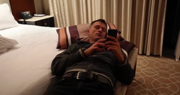 Homem Jovem Usando Smartphone Deitado Cama Correspondência Bate Papo Reserva — Vídeo de Stock