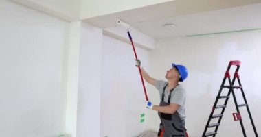 Tamirci tavanı silindirle boyuyor. Beyaz renkli 4K film yavaş çekim. Apartman ve konutların profesyonel ve yüksek kaliteli onarımı