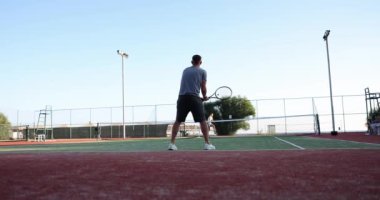 Tennis players play tennis on sunny day on court. Male tennis player hitting ball