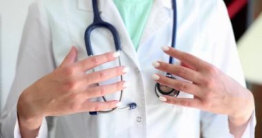 Doctor folds hands and adjusts stethoscope in clinic. Medical therapist cardiologist and health insurance