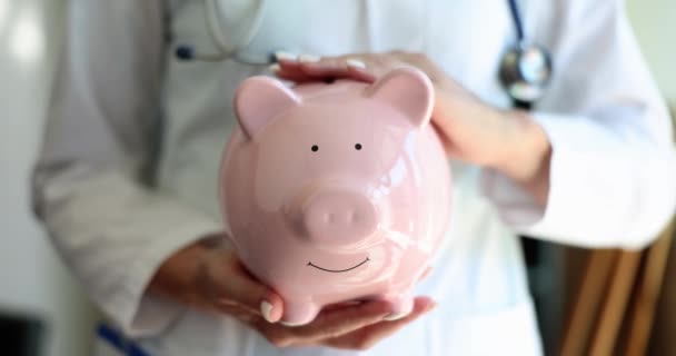 Female Doctor Holds Piggy Bank Medical Savings Insurance Health Care — Wideo stockowe