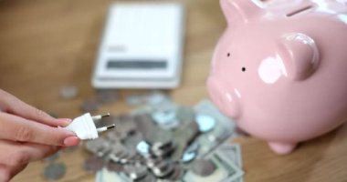 Fork in hand and piggy bank with coins and calculator. Energy saving