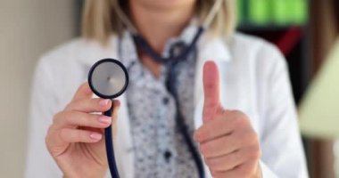 Doctor hand with thumbs up holds stethoscope. Recommendations for quality medical services and insurance