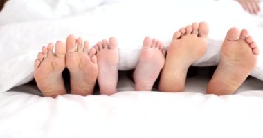 Family legs in bed parents and child. Family comfortable sleep bedroom or hotel