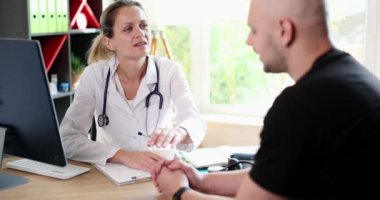 Female doctor consults depressed sad patient to clinic. Therapist talking to male client at consultation in hospital