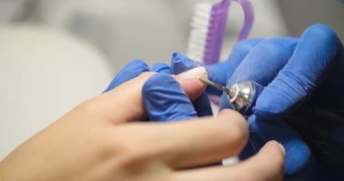 Process of hardware manicure for client in beauty salon closeup. Manicurists use electric nail drill to remove polish and cuticles from nails