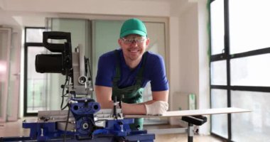 Portrait of smiling builder carpenter with machine for cutting laminate. Carpenter cuts laminate with power saw and floor repair services