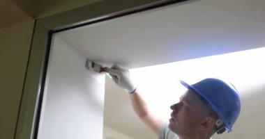 Hand painter painting with white paint on wall surface of doorway. Apartment painting and renovation with white paint