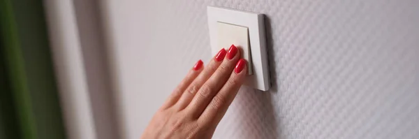 Woman hand presses white light switch. Stylish modern wall switch concept