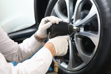 Garage master unscrews nuts to broken wheel of car. Tire service and auto service concept