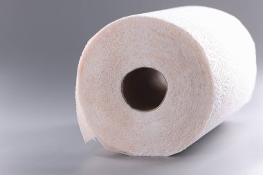 Roll of white toilet paper on gray background. Choosing quality toilet paper concept