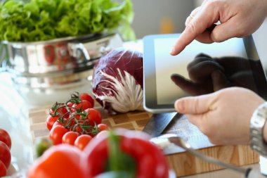Person holds tablet and is going to cook vegetables. Online recipe cooking vegetarian food concept
