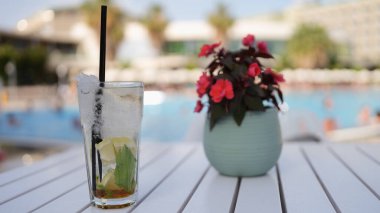 Summer cocktail with lemon and mint with ice on summer table pool. Summer soft drinks concept