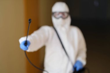 Person in protective suit spraying disinfectant. Concept disinfection service center