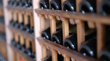Resting dusty wine bottles stacked on wooden racks in basement. Elite collectible expensive wine in cellar