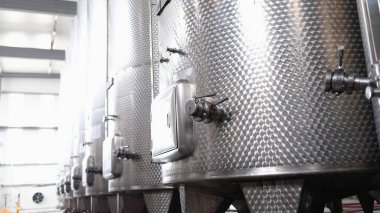 Modern automated winery with lines of metal tanks. Interior view of modern brewery with stainless steel barrels. Shop with a brewery