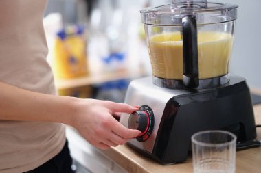 Woman is making smoothie or mixing dough in electric blender. Blender and food mixer concept