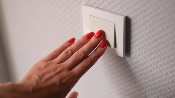 stock image Closeup of awoman hand is turned off on light switch at home. Power energy and electricity saving