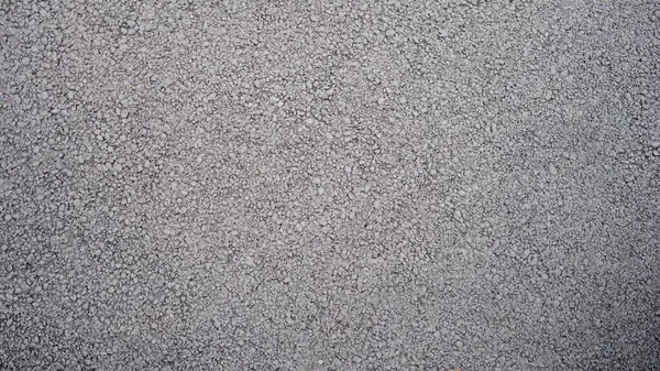Rough texture of wall made of small gray cement pebbles. Photo of crumbling stone wall made of cement and small stones
