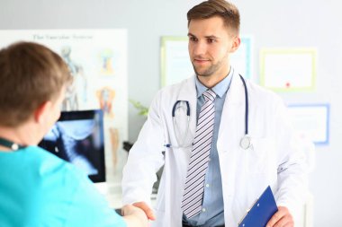 Doctor and patient shaking hands in clinic. Health insurance and services concept