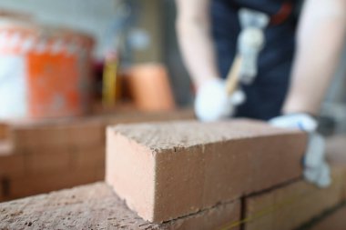 Closeup of industrial bricklayer laying bricks at construction site. Building brick walls concept