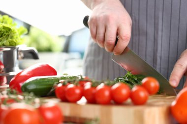 Cook cuts tomatoes and cucumbers on cutting board. Cooking vegetable salad concept