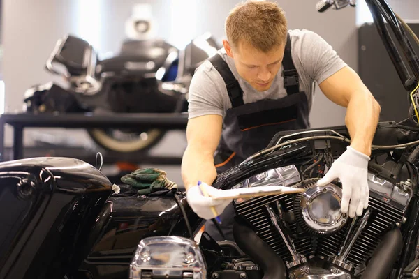 Master diagnoses and repairs motorcycle in workshop. Motorcycle maintenance concept
