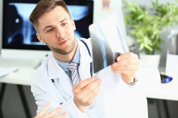 Male doctor examines x-ray of leg and arm in clinic. Medical diagnosis of fractures concept