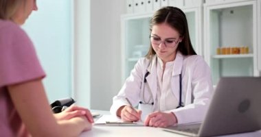 Female general practitioner listens to woman complaints at meeting in clinic. Gynecologist consulting and writing notes