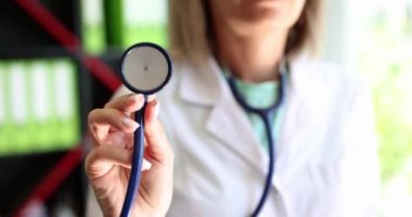 Kadın, elinde steteskop olan bir doktor, yakın plan. Pulmonoloğun muayenesi. Cihaz kardiyoloğu