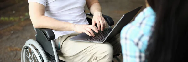 Man in wheelchair and woman work remotely while sitting in park. Freelance for people with disabilities concept
